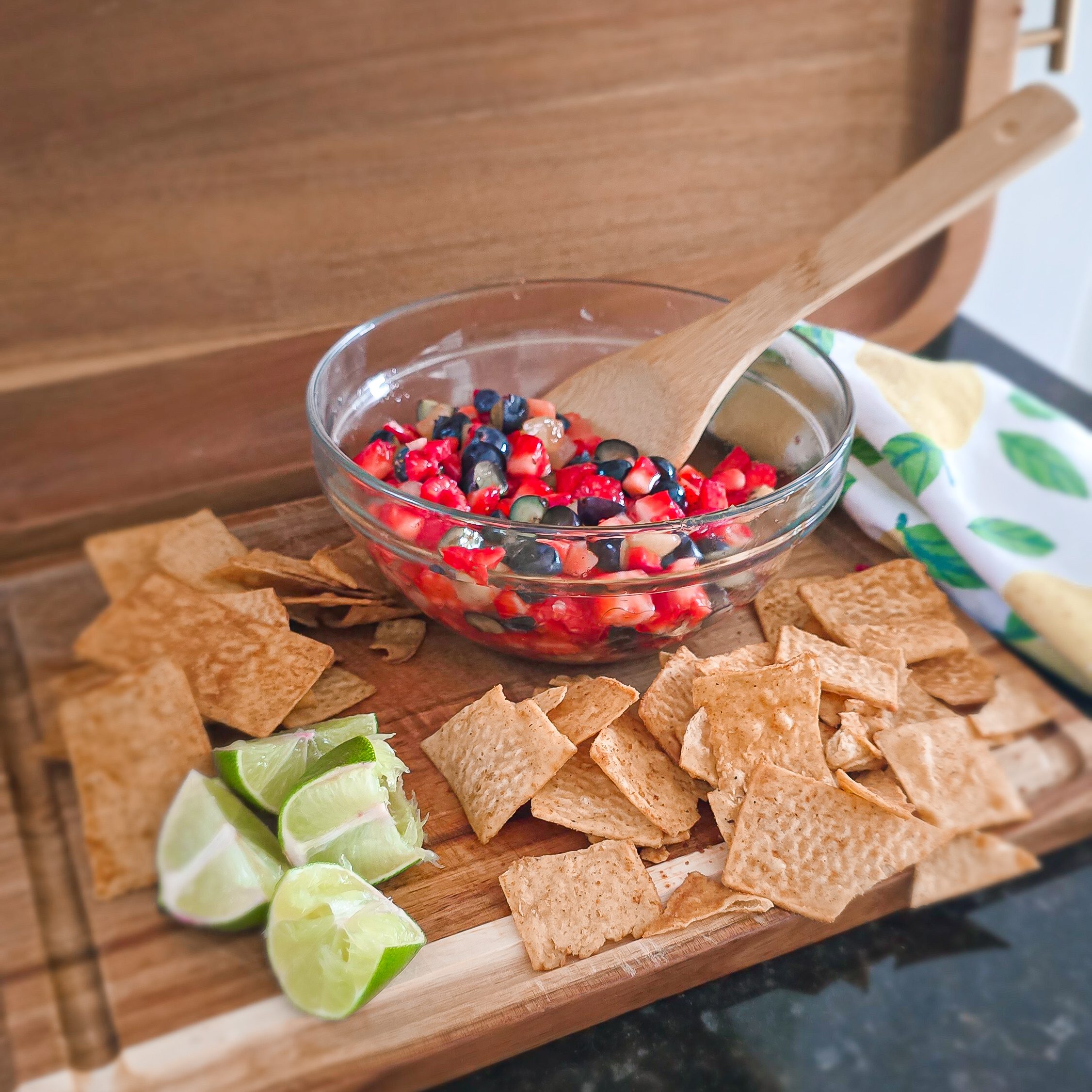 fruit salsa with churro chips and lime on a wooden cutting board
